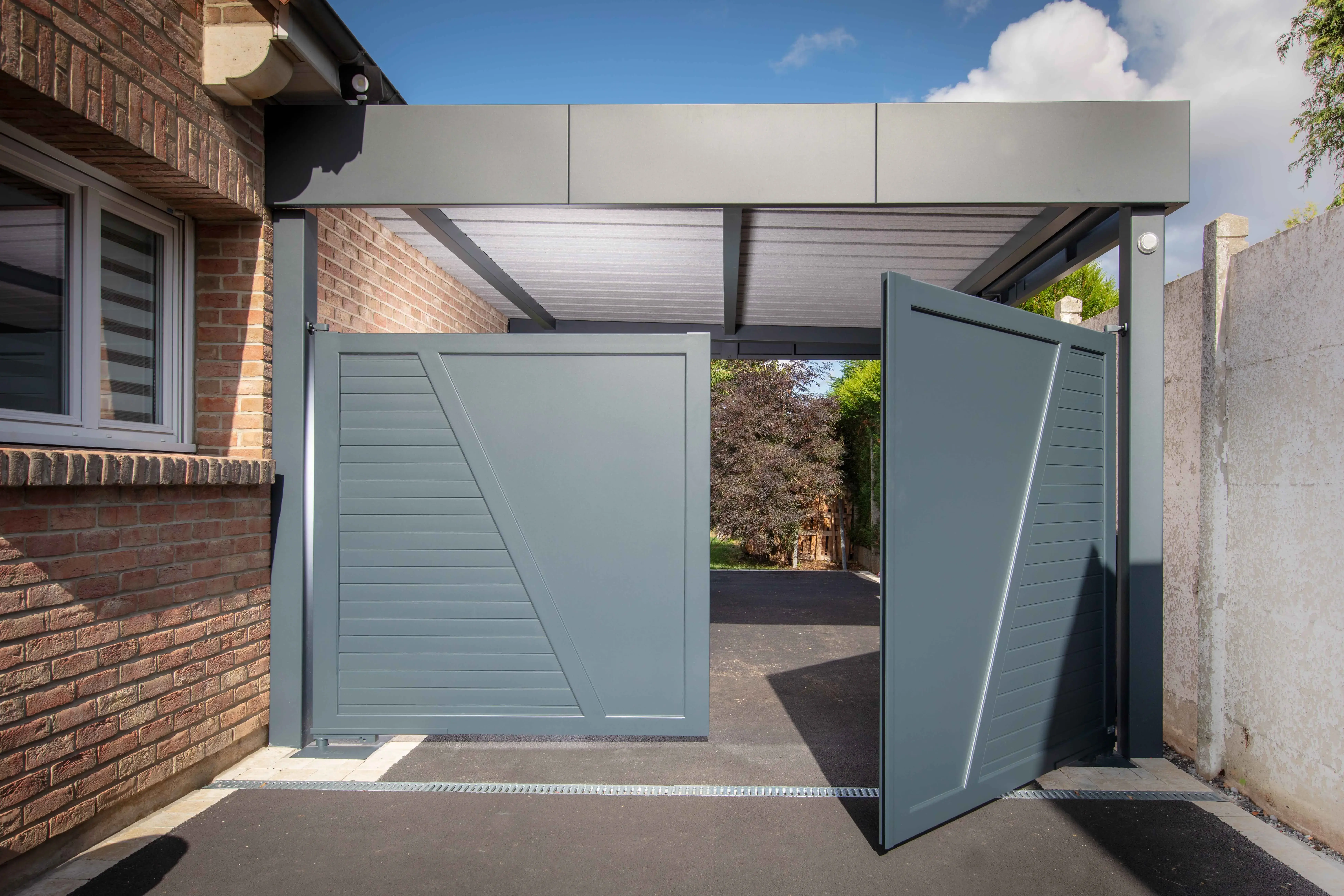 Carport aluminium ORION adossé sur mesure avec bandeau HORIZON et toiture bac acier – portail battant motorisé BERNAY en tôle pleine intégré sur poteaux – fabrication française EUROFACTORY