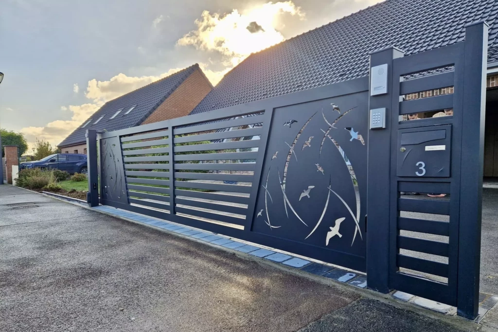 Portail coulissant motorisé et portillon en aluminium gris anthracite, création sur mesure avec découpe laser oiseaux et lignes dynamiques, installé dans le Nord de la France. Fabrication française Eurofactory