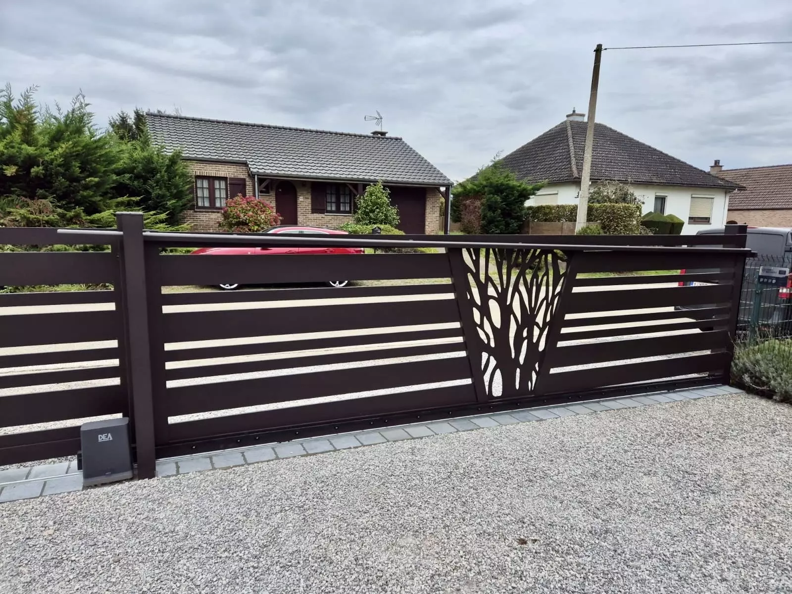 Vue intérieure du portail aluminium sur mesure coulissant sur pente avec décor laser et clôture assortie, finition brun gris RAL 8019 – réalisation Eurofactory Autreppe Belgique