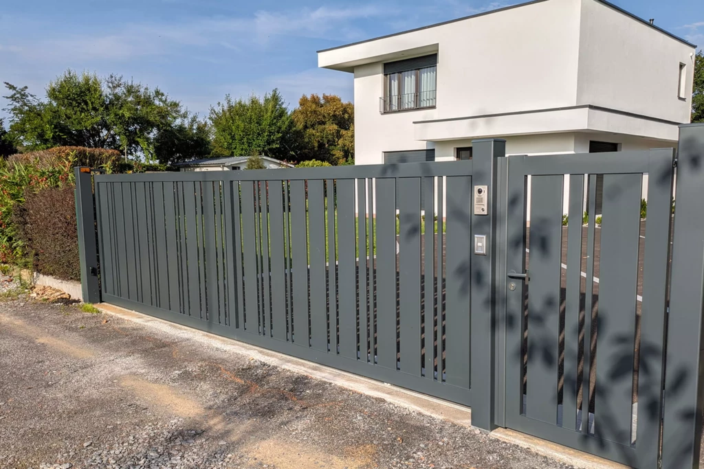 Portail DURANCE ajouré avec portillon assorti en aluminium gris anthracite, lattes verticales de tailles variées pour un effet rythmé et lumineux