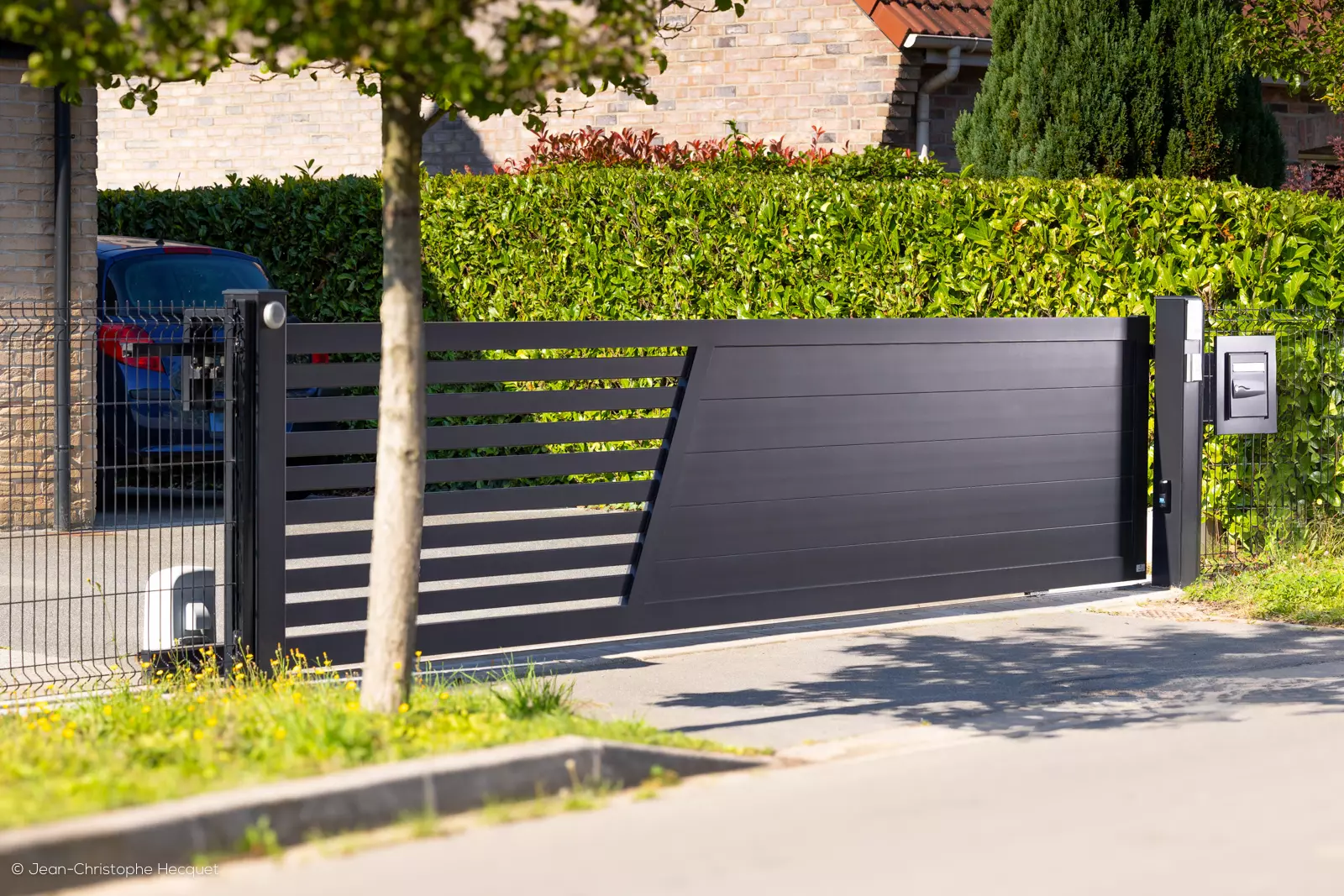 Portail coulissant aluminium sur mesure avec lames pleines de 200 mm, ajourage latéral et boîte aux lettres intégrée